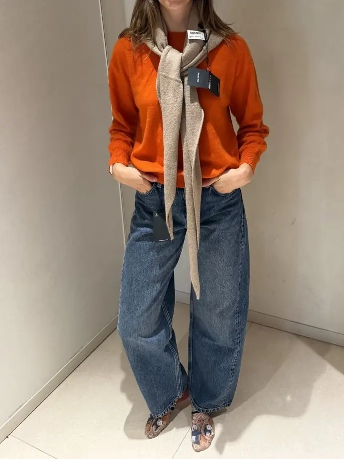 Orange sweater with a beige scarf and wide jeans, a fitting during shopping with a stylist in Lisbon