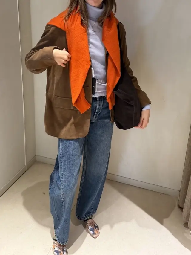 Suede blazer with an orange sweater over the shoulders